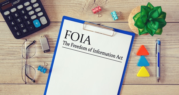 Carta con il FOIA del Freedom of Information Act sul tavolo, calcolatrice e bicchieri