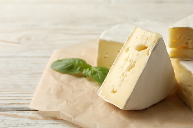 Carta da forno con formaggio camembert e basilico su fondo in legno