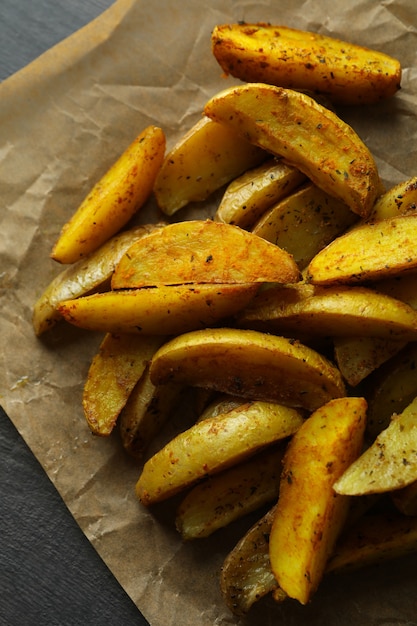 Carta da forno con spicchi di patate su texture scura