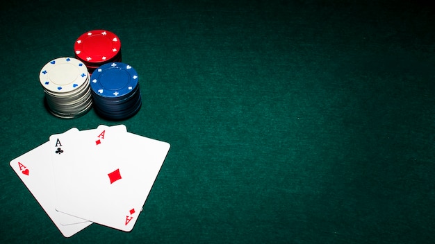 Carta da gioco di tre assi e pila di fiches del casinò sul tavolo da poker verde