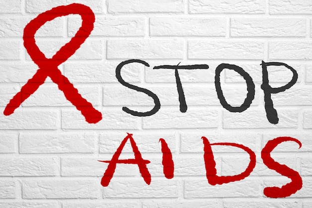 Carta da parati con testo scritto a mano. muro di mattoni bianchi con l'iscrizione stop aids