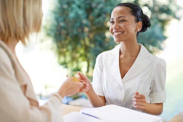 Carta di accesso e donna che paga con un addetto alla reception per la prenotazione di alloggi o hotel Sorriso felice e ospite amichevole che effettua il pagamento e il check-in con una persona di sesso femminile al banco della reception