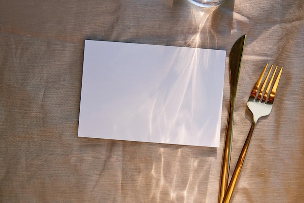 Carta di cancelleria minimalista mock up con ombre dure luce solare e posate Vista dall'alto spazio per la copia Mockup di invito per cartoline con design del menu