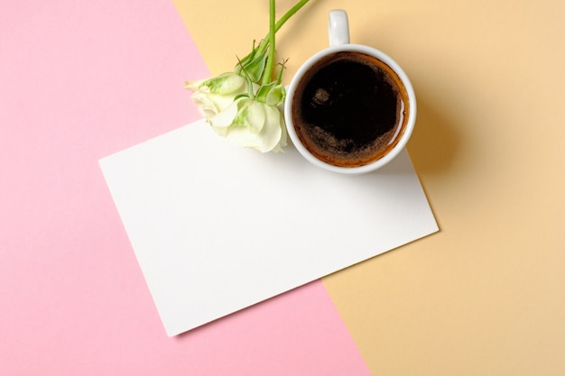 Carta di carta bianca con copia spazio, tazza di caffè e fiori di rose bianche