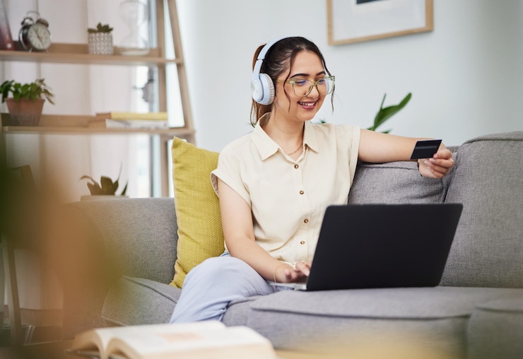 Foto carta di credito donna e laptop con cuffie in casa per il pagamento digitale password fintech e acquisti online conto computer cliente donna felice e codice bancario per aggiornare l'abbonamento musicale