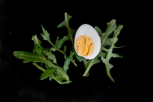 Carta di Pasqua con uovo su sfondo nero e foglie verdi