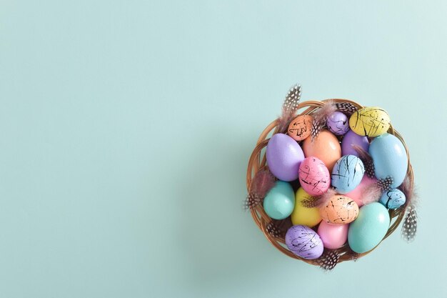 Carta di Pasqua Minimalismo Un nido con uova di Pasqua dipinte e piume Spazio di copia Vista dall'alto piatta