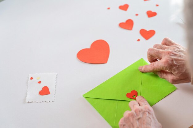 Carta di San Valentino fai da te Le mani della donna anziana stanno chiudendo una busta