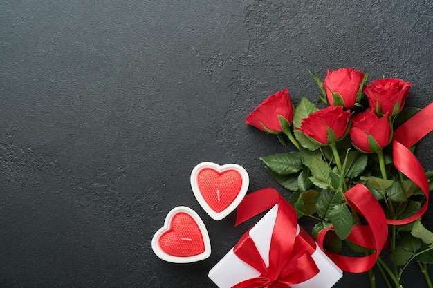 Carta di San Valentino Fiori rossi rosa biscotti brownie e caramelle al cioccolato su confezione regalo a forma di cuore con vino su sfondo nero Biglietto di auguri per la festa della mamma o della donna Vista dall'alto piatto