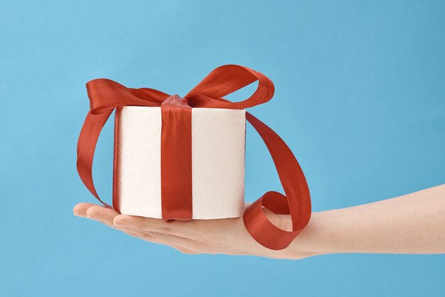 carta igienica stretta della mano avvolta in un nastro festivo come regalo su fondo blu