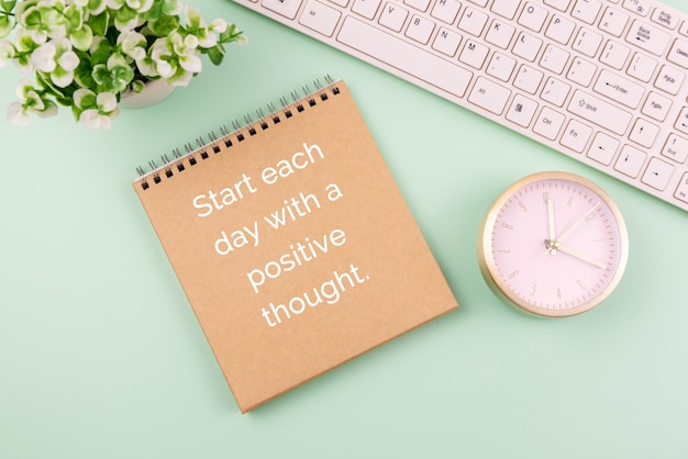 Carta marrone, tastiera del computer, sveglia e testo iniziano ogni giornata con un pensiero positivo
