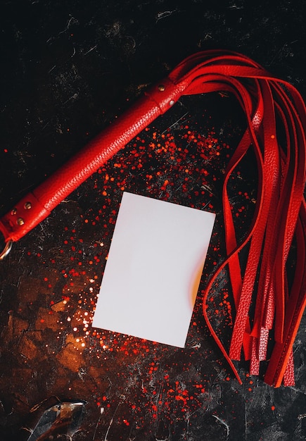 carta mockup, mockup di un foglio bianco di giocattoli bdsm di carta, frusta in pelle rossa su sfondo nero con