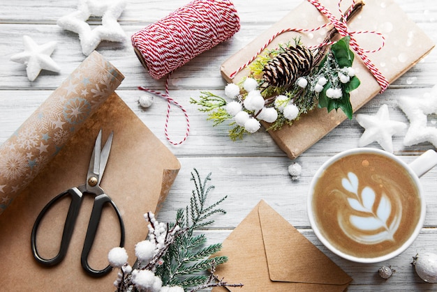 Carta natale e felice anno nuovo con tazza di caffè, pino, abete, scatole regalo su fondo di legno bianco, vista dall'alto