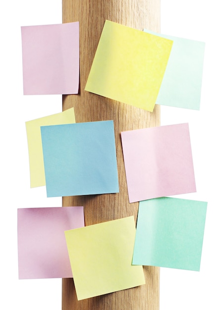 Carta per appunti di diversi colori su un supporto rotondo in legno isolato su bianco