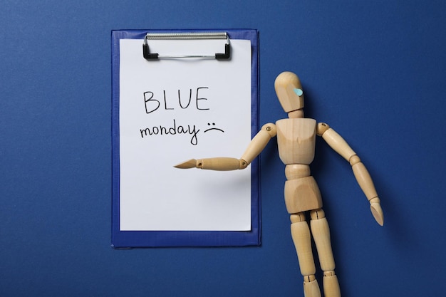 Carta per cartelle con testo Blue Monday e uomo di legno su sfondo blu vista dall'alto