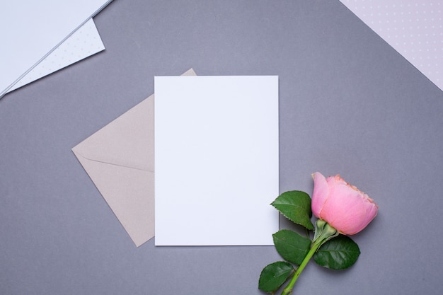 Carta regalo e busta con rosa rosa su grigio