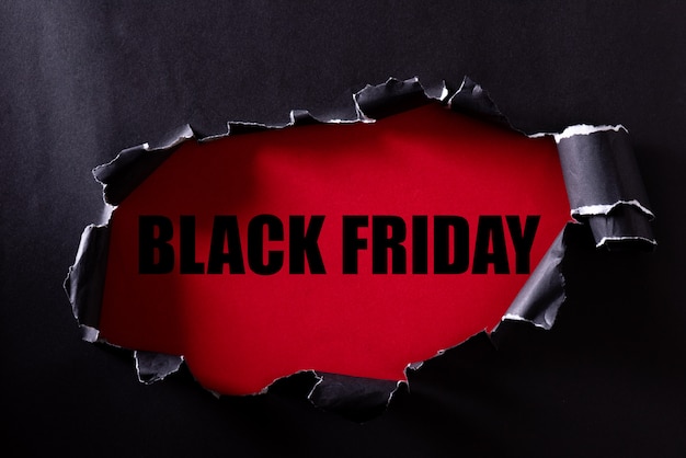 Carta strappata nera e testo Black Friday su un rosso.