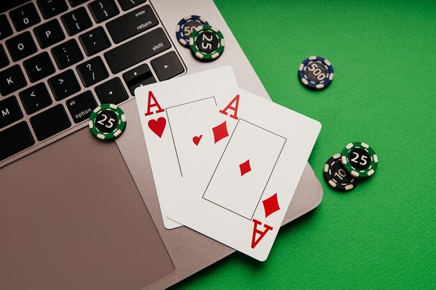 Carte da gioco con assi e fiches su un laptop con sfondo verde Scommesse da casinò online