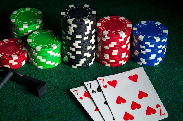 Carte da poker con tris o combinazioni di set nel casinò. Patatine e rastrello sul tavolo verde