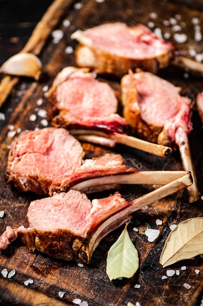 Carte di agnello grigliato su un tagliere con foglie di alloro