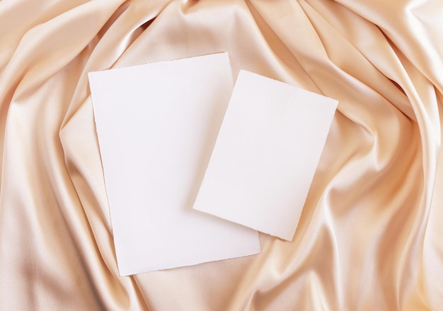 Carte in bianco su tessuto di seta beige drappeggio vista dall'alto saluto o mockup di nozze