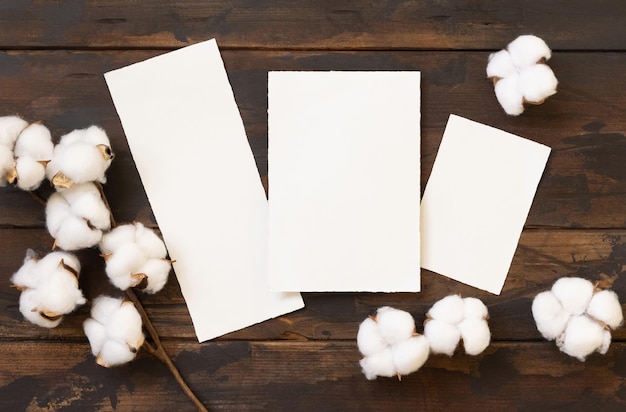 Carte vuote con vista dall'alto di fiori di cotone su mockup di matrimonio in legno marrone scuro