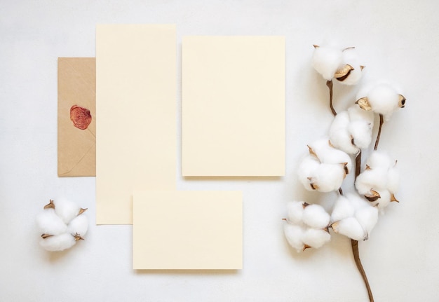 Carte vuote e busta con vista dall'alto di fiori di cotone sul modello di matrimonio bianco