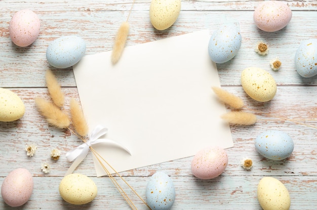 Cartella di auguri di Pasqua con uova di Pasqua e spikelets su sfondo di legno chiaro con spazio per la copia