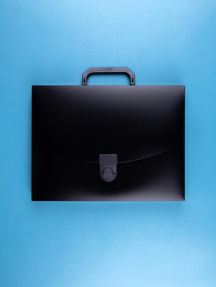 Foto cartella di borsa di plastica nera per documenti e articoli scolastici su un tavolo blu brillante