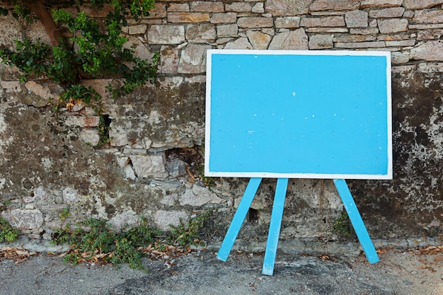 Cartello bianco blu in piedi vicino a un vecchio muro di pietra, copia spazio per il tuo testo