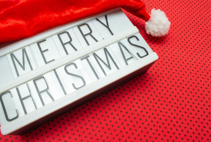 Foto cartello luminoso con il cappello di babbo natale scritto buon natale su uno sfondo rosso