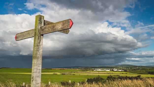 Cartello stradale trasversale del primo piano. Cielo piovoso Irlanda.