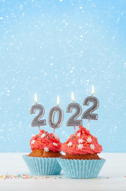 Cartolina d'auguri di Natale con cupcakes e nuove candele anno 2022