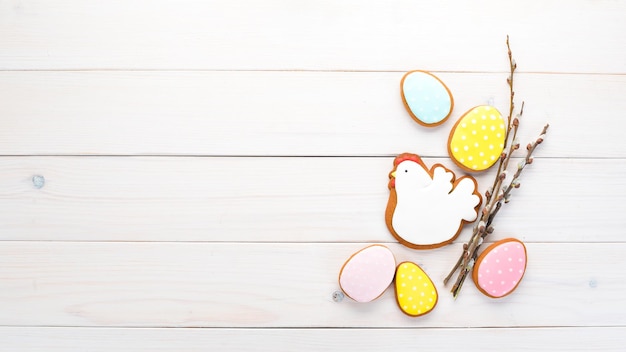 Cartolina d'auguri di Pasqua con pan di zenzero colorato e dolci. Su uno sfondo di legno bianco. Vista dall'alto. Spazio libero per il tuo testo.