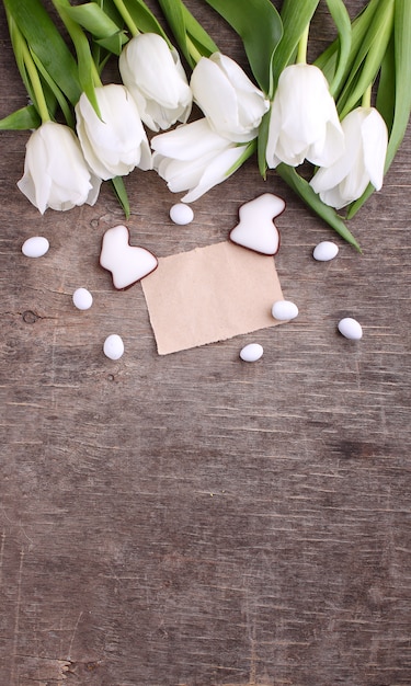 Cartolina d&#39;auguri di Pasqua felice con tulipano bianco e uova e coniglietto di cioccolato, fondo rustico.