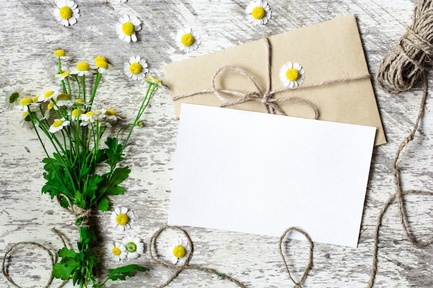 Cartolina d'auguri e busta bianche in bianco con i fiori della camomilla