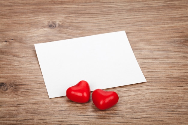 Cartolina d'auguri in bianco di San Valentino e cuori di caramelle sul tavolo di legno