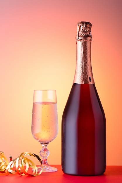Cartolina di Natale con bicchiere di champagne, bottiglia sul rosso