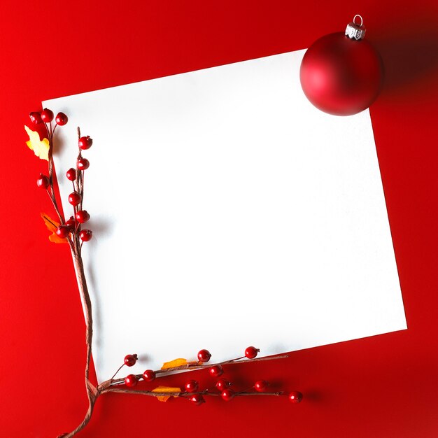 Cartolina di Natale con palla e biancospino su sfondo rosso