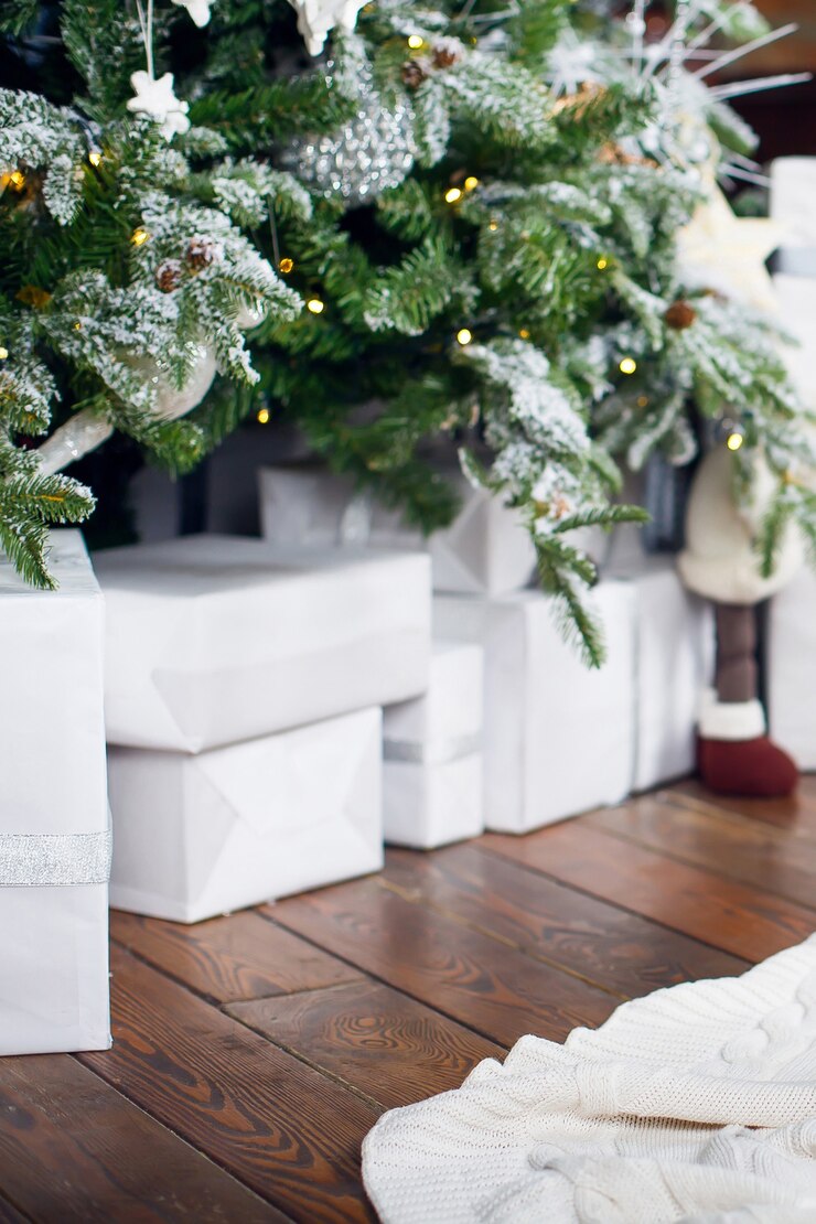 Cartolina di Natale I regali in scatole in confezione semplice giacciono sotto l'albero di Natale su un pavimento di legno marrone