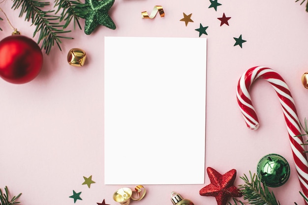 Cartolina di Natale piatta Disposizione moderna della cartolina d'auguri e decorazione natalizia rossa su rosa Estetica