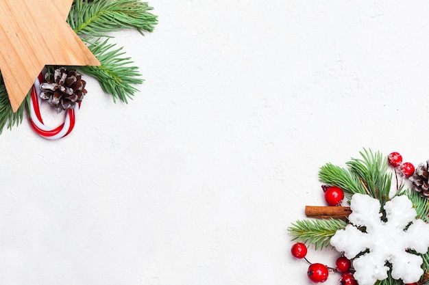 Cartolina di Natale sfondo angolo composizione con fiocco di neve verde Natale ramo di abete bacche di agrifoglio rosso e baubles su stucco bianco intonaco texture di sfondo