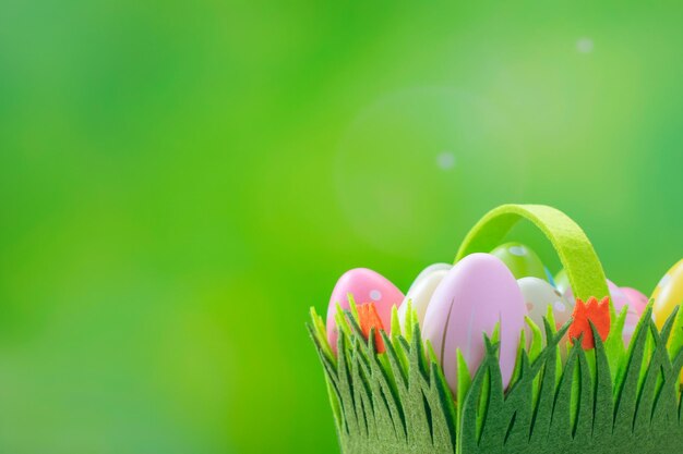 Cartolina di Pasqua felice Uova di Pasqua in un cestino su uno sfondo verde con spazio per il testo Uova decorate multicolori su uno sfondo primaverile