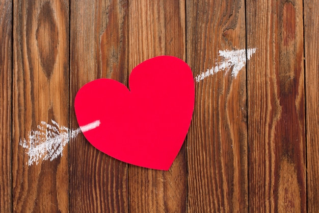 Cartolina di San Valentino per San Valentino Il cuore di carta rosso è stato trafitto da una freccia disegnata con il gesso su assi di legno.