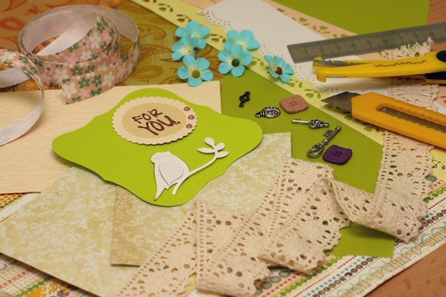 Cartolina scrapbooking fatta a mano e strumenti sdraiati su un tavolo