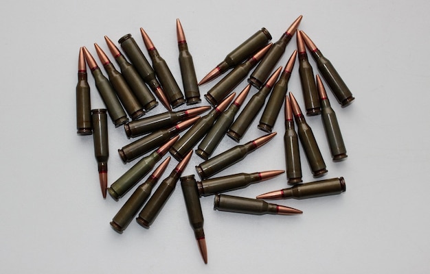 Cartucce unitarie con proiettili in lega di rame per fucile d'assalto sparsi su una superficie bianca