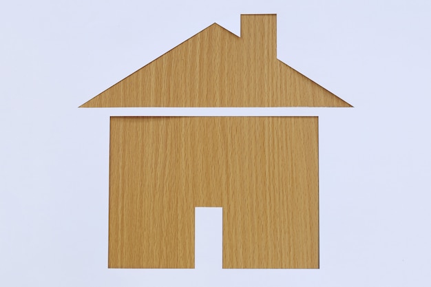 Casa a forma di carta su uno sfondo di legno marrone.
