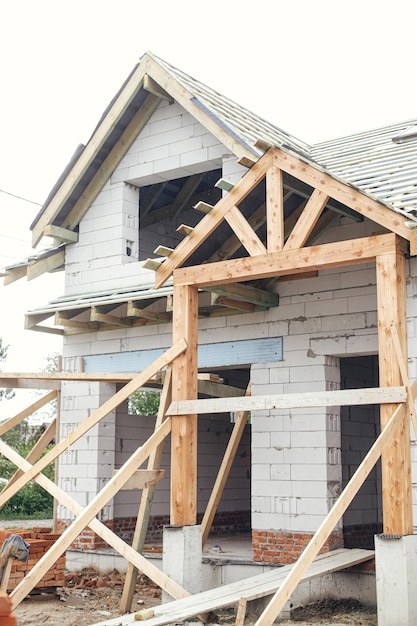 Casa al grezzo Struttura del tetto in legno con barriera al vapore e abbaino su pareti in blocchi con finestre Costruzione di una nuova casa colonica moderna Capriate in legno Travi e travi su blocchi di cemento cellulare