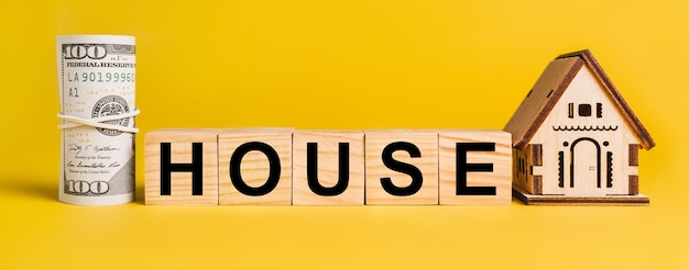 CASA con modello in miniatura di casa e denaro su sfondo giallo. Il concetto di affari, finanza, credito, tasse, immobili, casa, alloggio