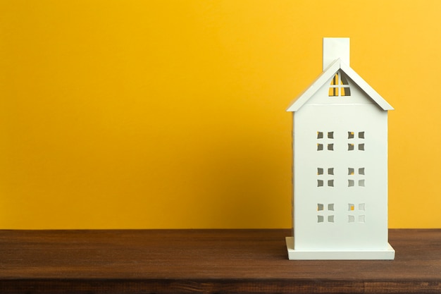 Casa del giocattolo su sfondo giallo. Immobiliare, alloggi in affitto e concetto di casa.